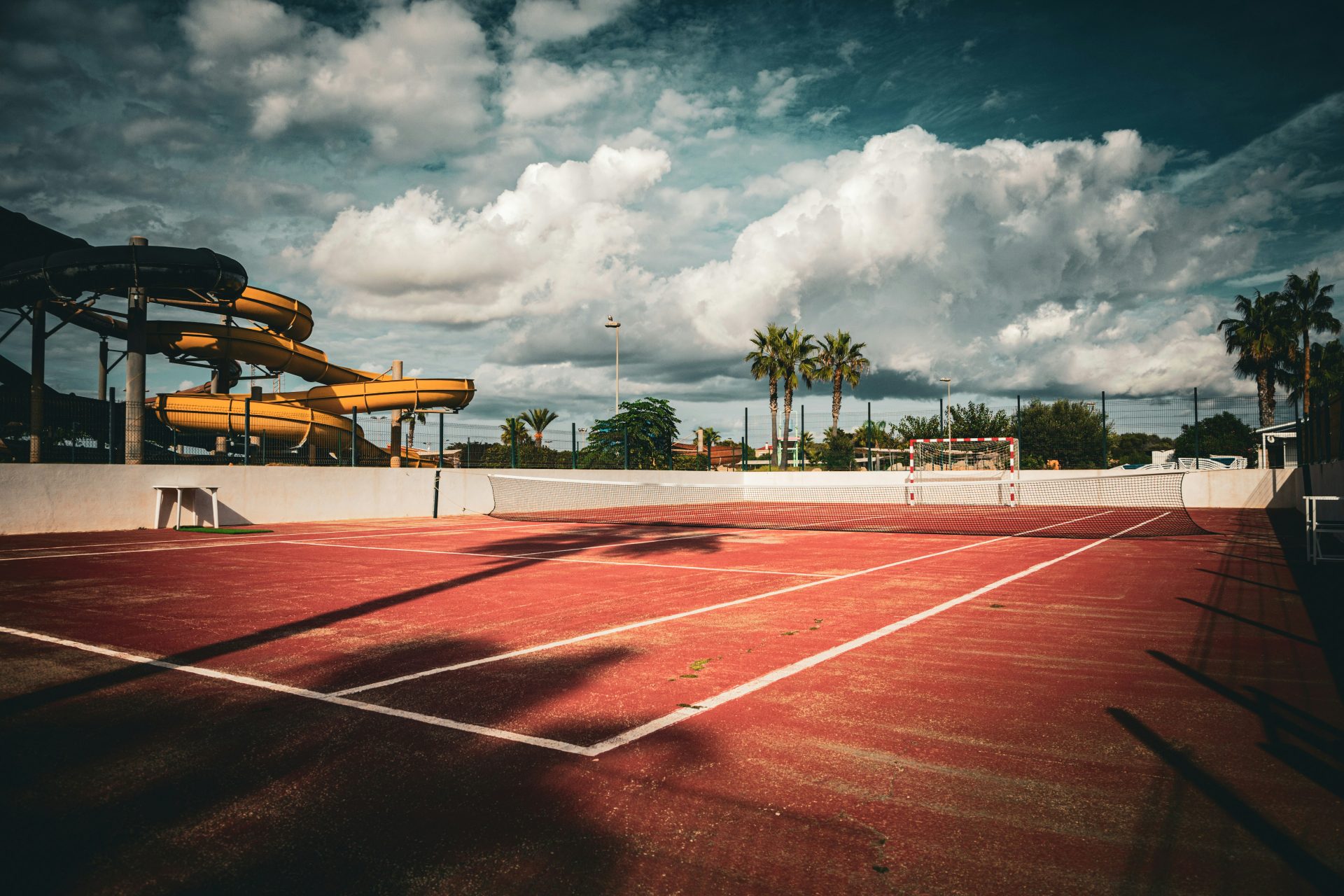 A tennis court with a slide in the background